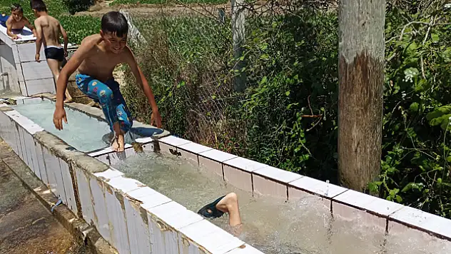 Sıcaktan bunalan çocuklar yalakta serinledi