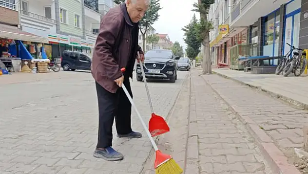 Elinde süpürge ve faraşla temizlik yapıyor