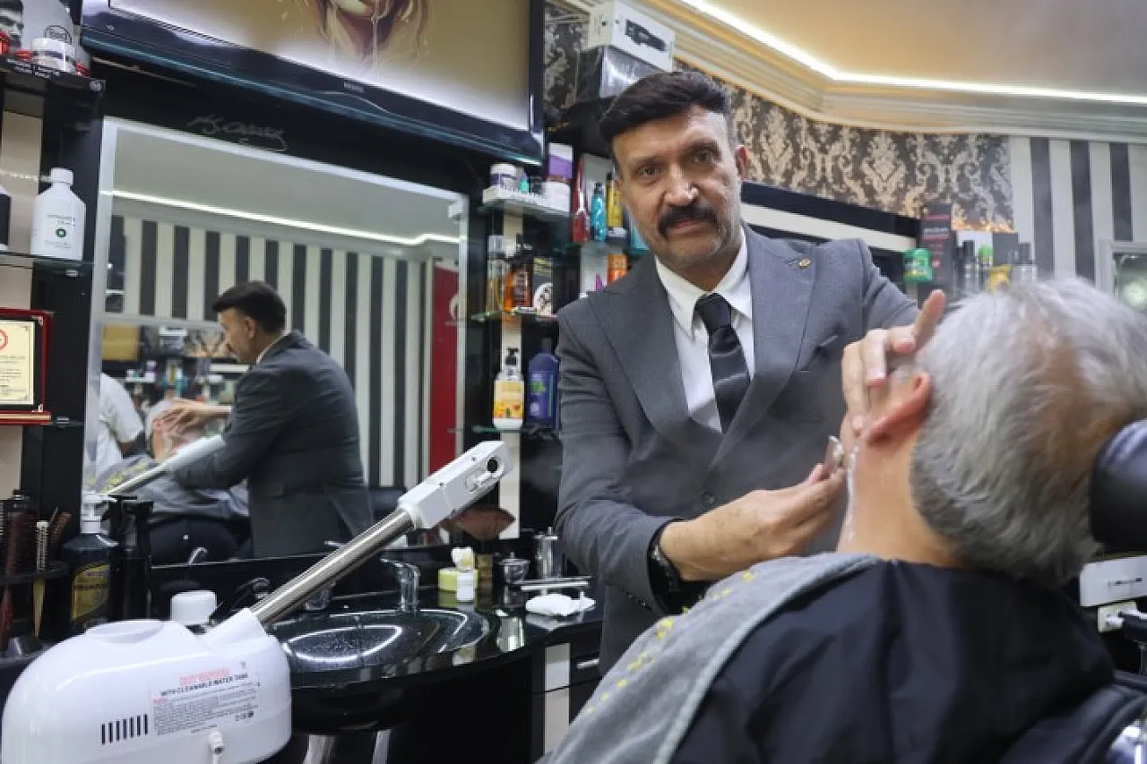 Müşterilerini takım elbiseyle traş ediyor
