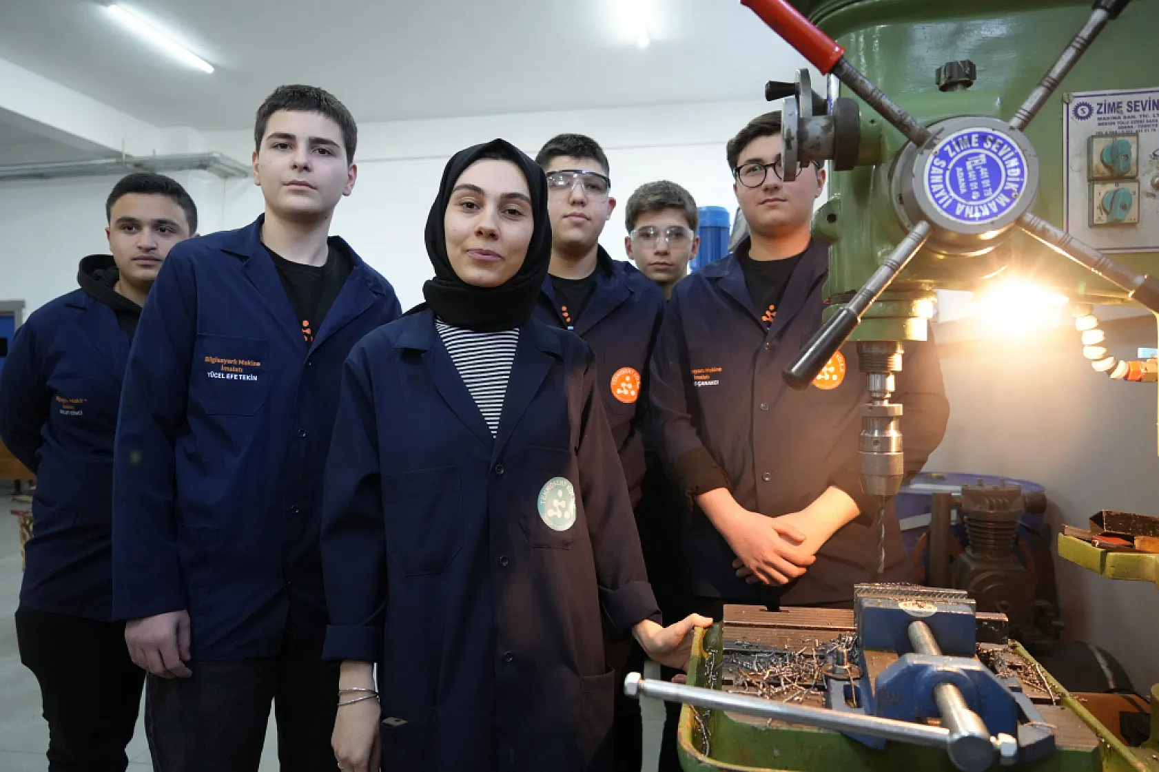 Kadın öğretmen torna tezgahında öğrencilere üretimi öğretiyor