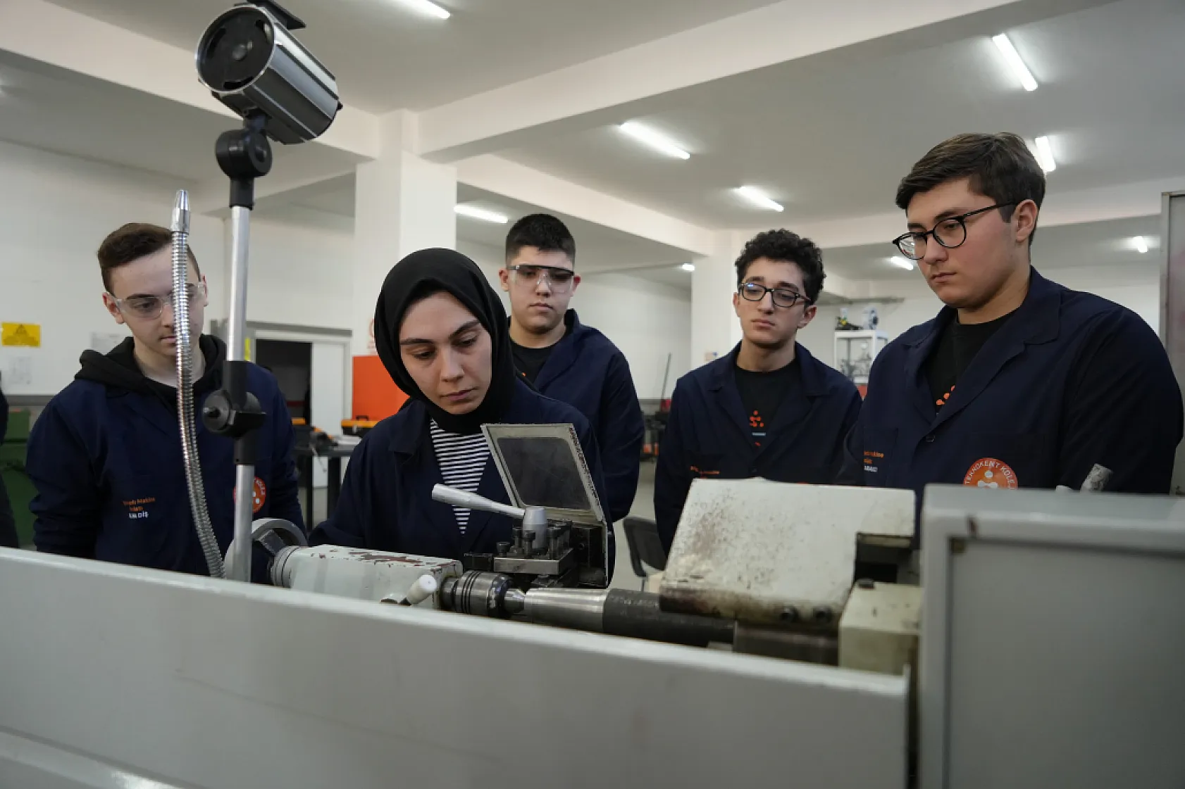 Kadın öğretmen torna tezgahında öğrencilere üretimi öğretiyor