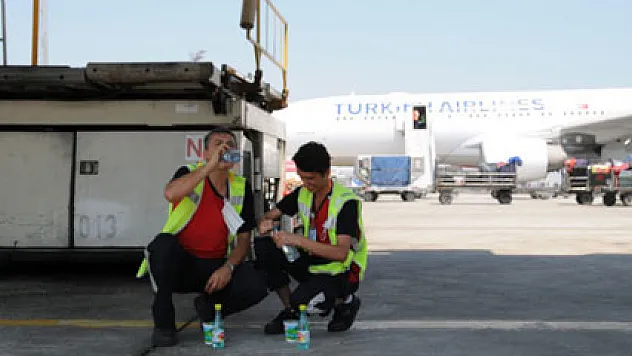 Sıcaktan bunalan işçiler uçakların altında serinledi