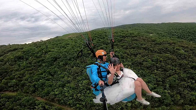 Gelinliğini giyip yamaç paraşütü yaptı